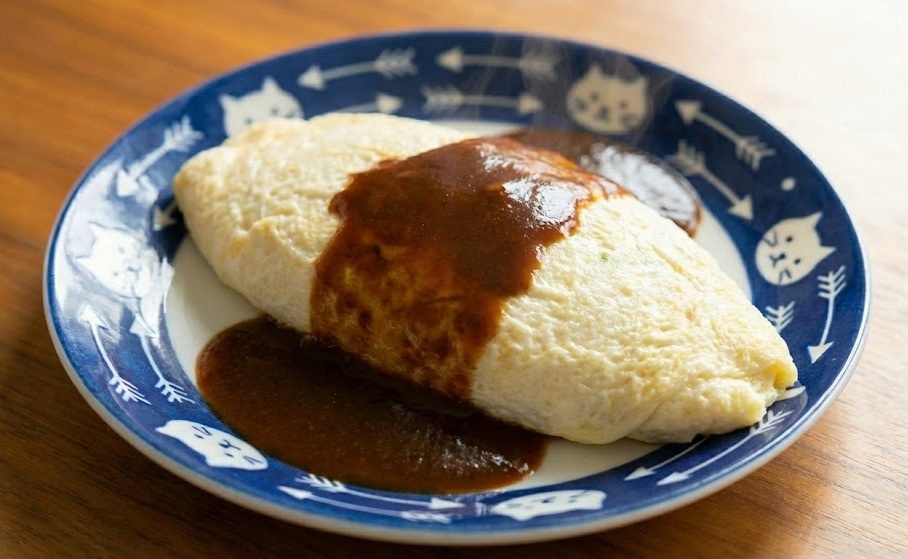 余った白身と全卵で作る節約オムレツの完成写真。猫の柄の皿に盛り付けられ、ソースがかかっている